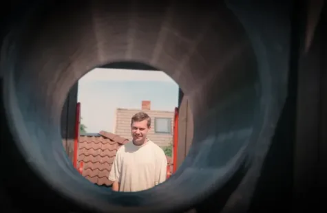 Barnehageansatt ser gjennom et leike stativ og smiler
