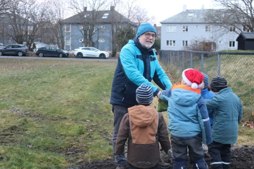 Rolv Lundheim fra naturfagseksjonen på DMMH deler ut villblomstfrø til barnehagebarna som hjelper til med å så.